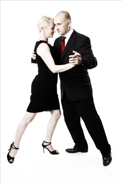 David and Ann in a tango A-frame, leaning together against a white studio backdrop