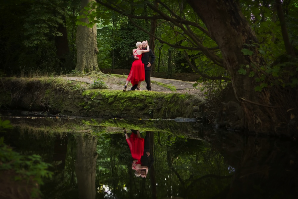 David and Ann dancing beside a pond, their embrace mirrored in the still water